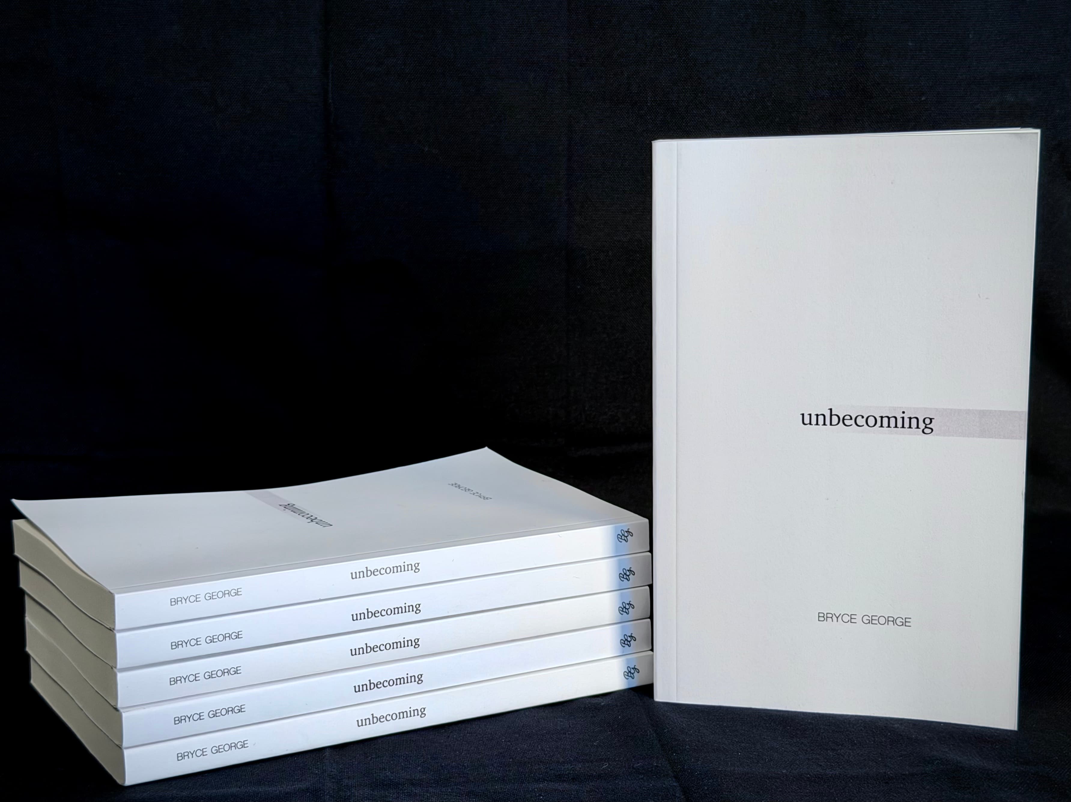 Several copies of Unbecoming arranged together against a dark background.